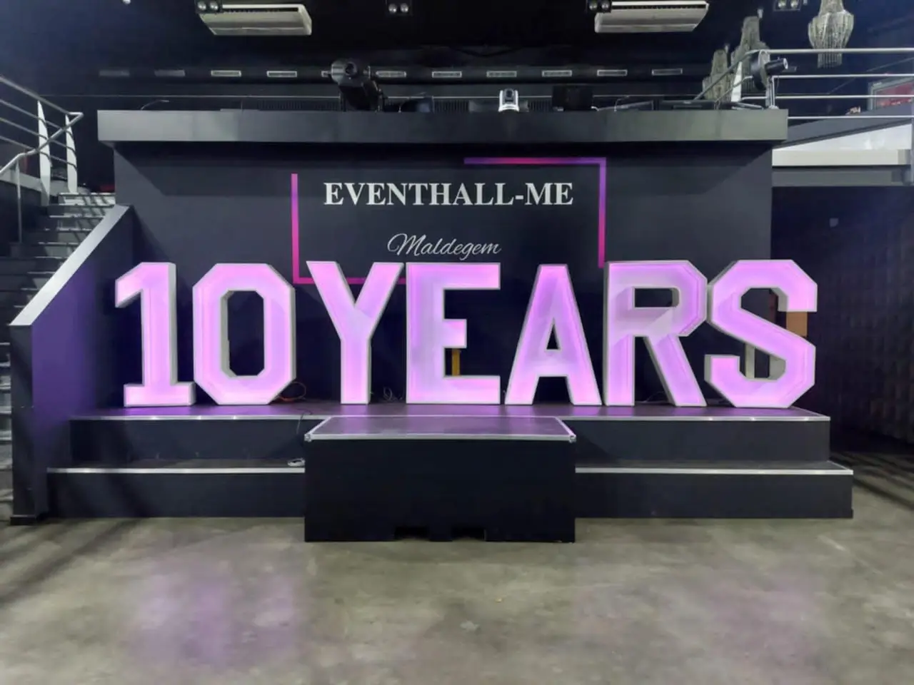 10 YEARS in verlichte letters op een podium tijdens een bedrijfsfeest.