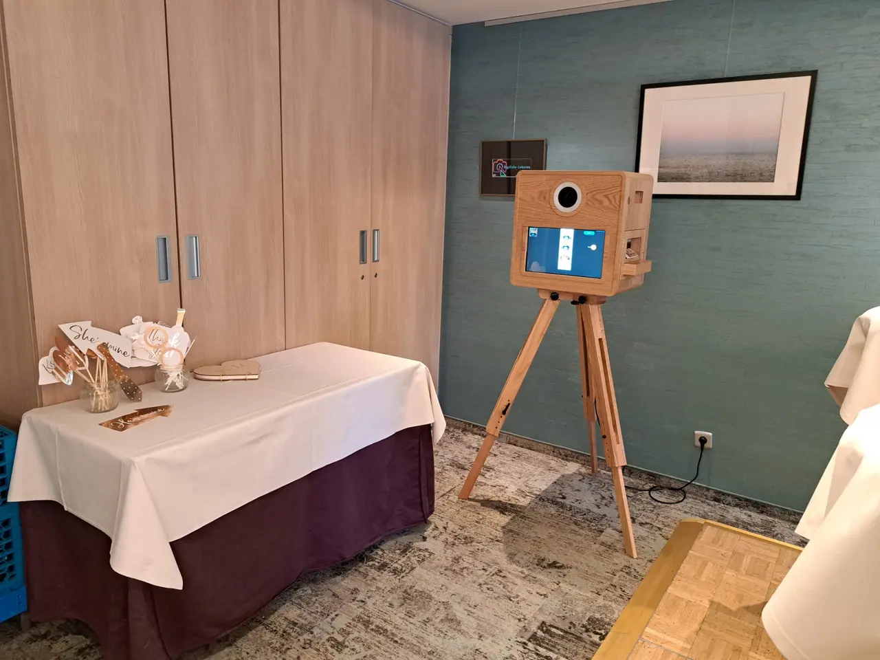 De FrameBooth, een houten photobooth op een houten statief, naast een gedekte tafel.