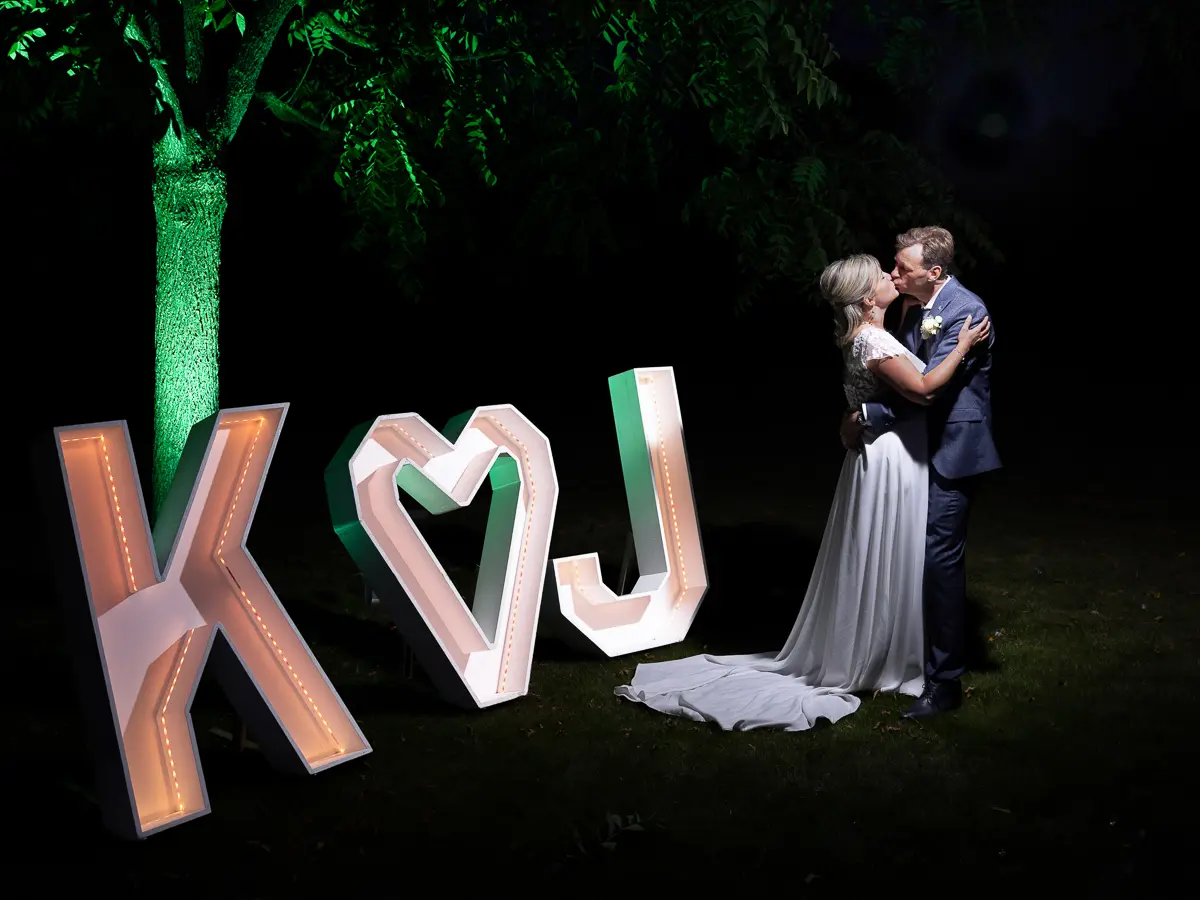 Een bruidspaar bij de letters K en J met een hart, in koraalrood licht.