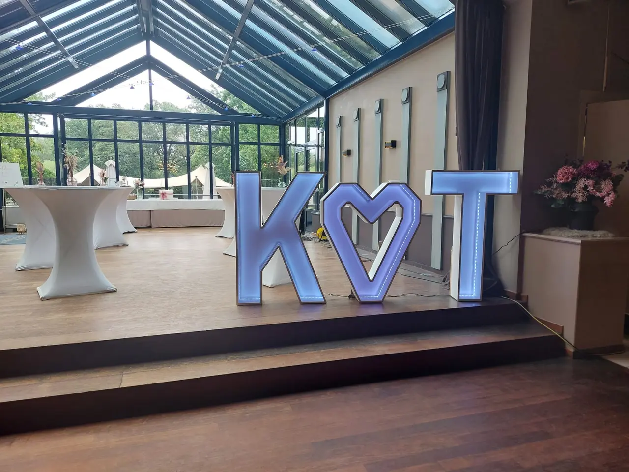 De letters K en T met een hart, in een orangerie bij een trouwfeest.