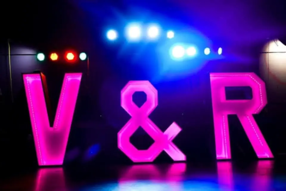 De letters V en R in fel roze licht op een podium.