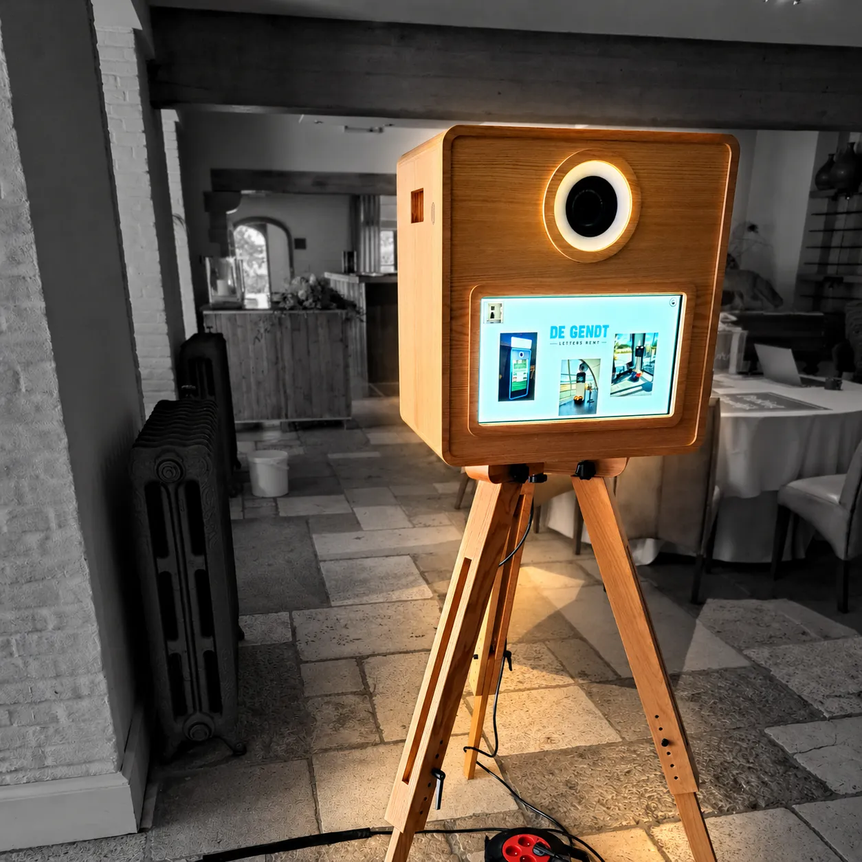 De FrameBooth op zijn houten statief, in een zaal met een stenen vloer.