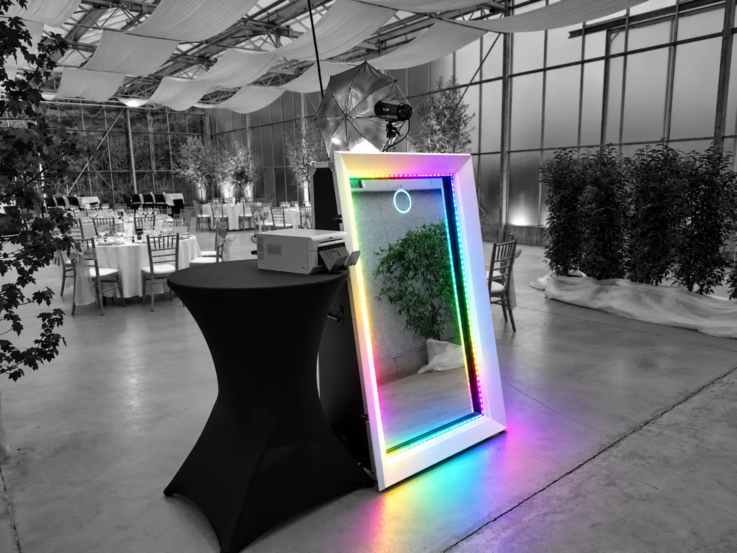 De Glammirror, een spiegel met een gekleurde ledrand, naast een statafel in een feestzaal van glas.